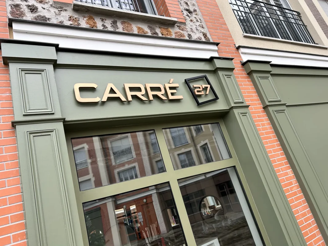 Enseigne CARRÉ 27 en lettres dorées sur une façade vert sauge.