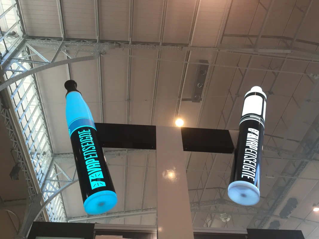 Gros plan sur deux colonnes lumineuses suspendues, bleue et noire, sur un stand de salon.