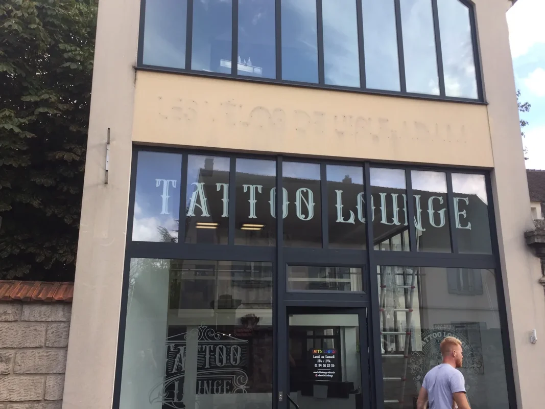 Vitrine de Tattoo Lounge avec lettrage sur les baies et la porte, passant à droite.